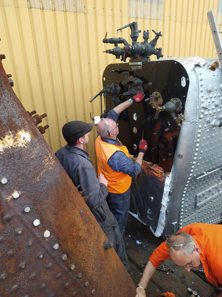 Paul Spence, Chris Field and Nigel Hanson seen fitting firebox backhead lagging and cladding on 25th May. Photo: Nick Willcox